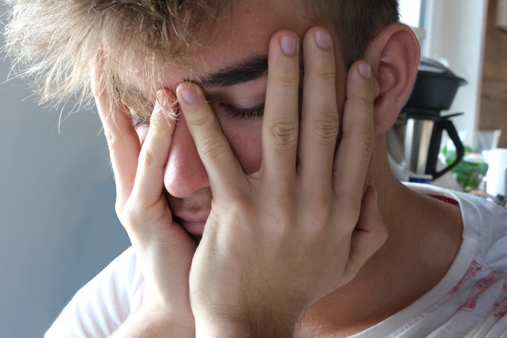 person holding their head, overwhelmed, anxious